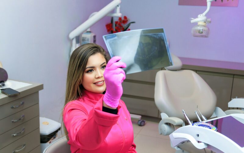 a woman sitting in a dentist chair holding up a mirror