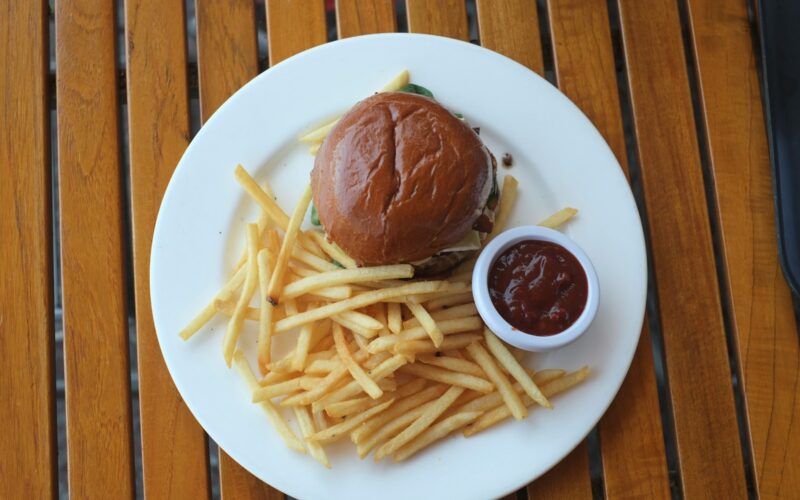 A burger and fries sit on a white plate.