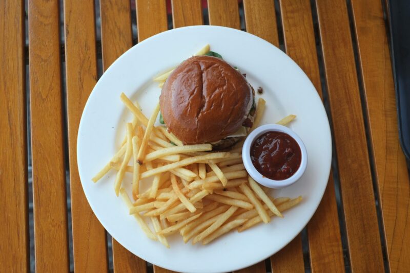 A burger and fries sit on a white plate.