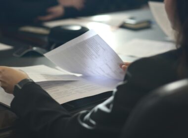 a woman sitting at a table reading a paper