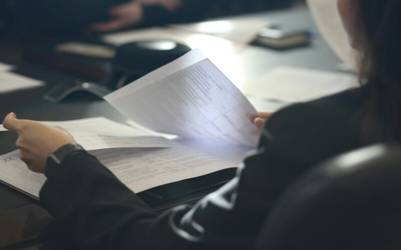 a woman sitting at a table reading a paper