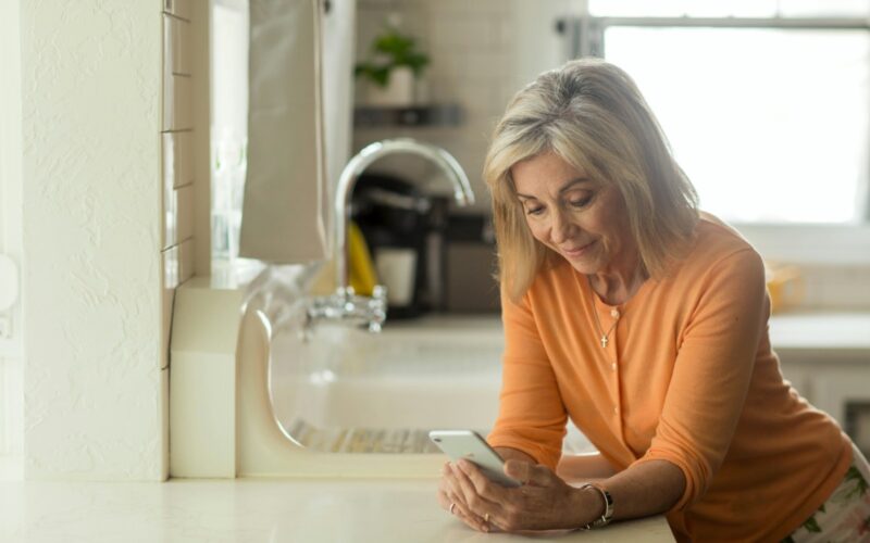 woman in orange long sleeve shirt using white smartphone