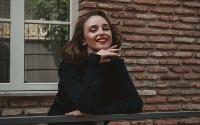 a woman leaning on a rail in front of a brick building